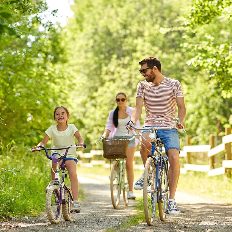 Família de bicicleta num percurso arborizado